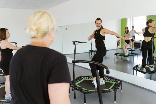 Instructor Viola Honzová smiling while jumping on a trampoline during a Jumping class in Brno